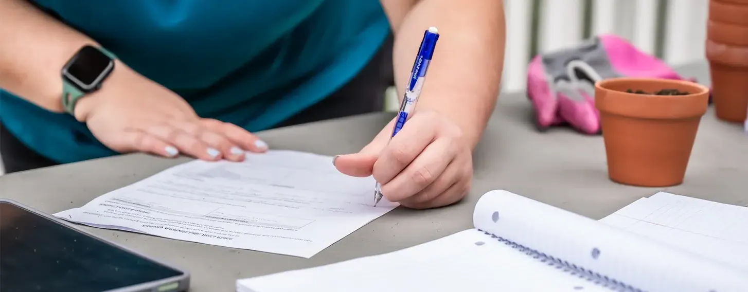 A student filling out paperwork on a desk